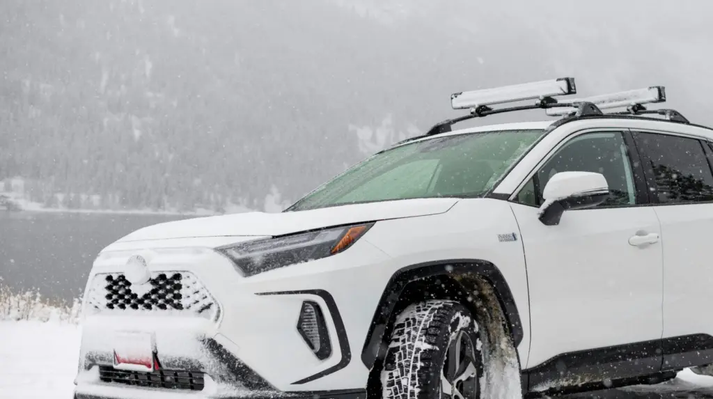 An SUV driving in the snow with ski and snowboard roof racks