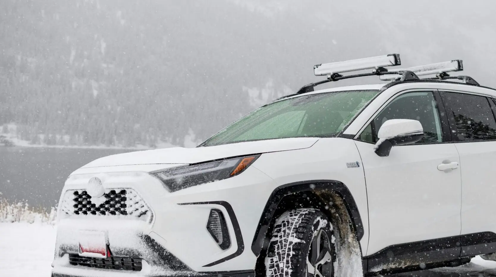 An SUV driving in the snow with ski and snowboard roof racks