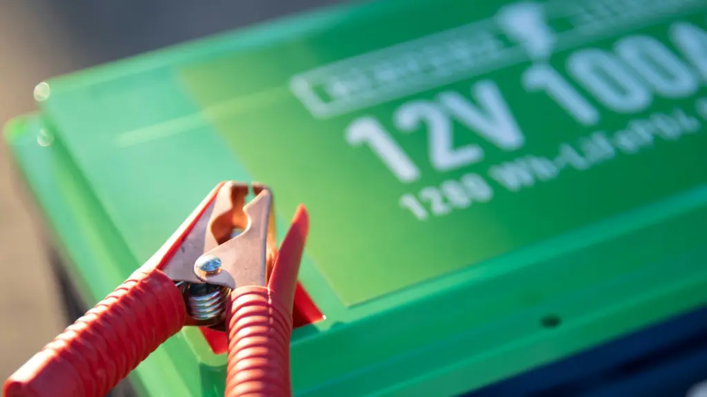 A red jump cable clamp on a battery